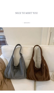 Detailed view of large woolen tote bags in grey and brown on a white fabric sofa
