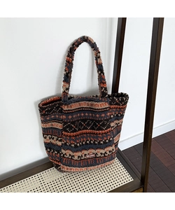 Detail of plush tote bag featuring bohemian geometric patterns and leather brand label