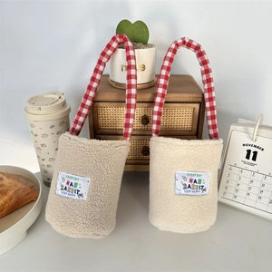 Close-up of plush fleece water bottle bags with red checkered handles in a cozy setting