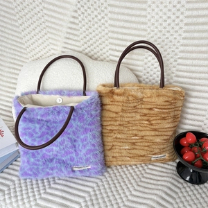 Detail of plush leopard print tote bag with brown leather handles and magnetic closure