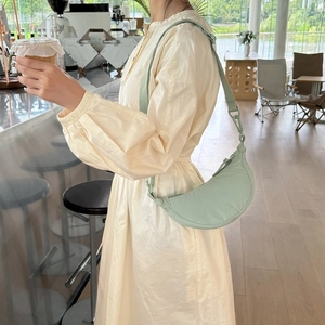 Adjustable light green nylon dumpling crossbody bag worn by a model in a modern cafe