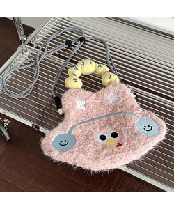 Detail of pink plush cartoon crossbody bag with embroidered eyes and woven strap