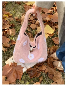 Pink plush tote bag with white floral embroidery placed on autumn leaves detail