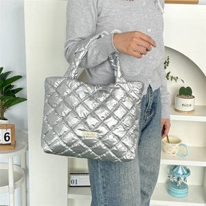 Detail of silver quilted handbag with metallic finish and padded square texture