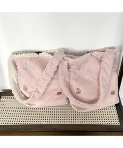 Detail of pink plush tote bag with Christmas embroidery and fleece trim on a bench