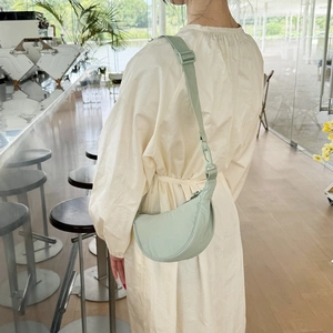 Adjustable light green nylon crossbody bag styled with a white dress in a bright cafe