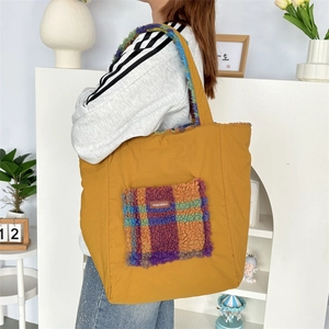Detail view of mustard yellow tote bag with colorful plaid plush pocket and soft shoulder strap