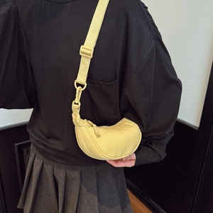Detail of pale yellow crescent bag with adjustable wide strap and water-repellent nylon fabric