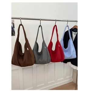Row of canvas tote bags in brown, grey, red, and blue colors hanging on a metal rack