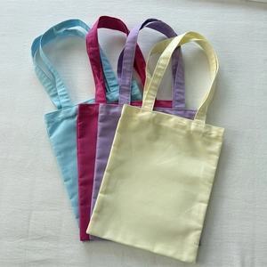 Flat lay of colorful canvas tote bags in blue, rose, purple and yellow on white texture