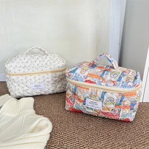 Vue détaillée de trousses de toilette matelassées à motifs floraux avec poignée de transport