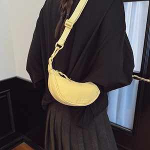 Light yellow nylon crescent crossbody bag with adjustable strap worn by model
