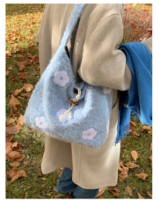Detail of blue plush tote bag with flower embroidery and a wooden toggle closure