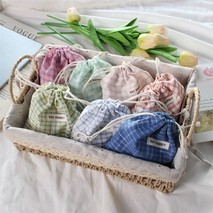 Detailed view of plaid drawstring pouches in assorted colors inside a woven basket