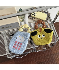 Detail of plush cartoon crossbody bags featuring cute monster and bunny designs on glass