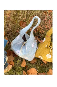 Detail of plush floral tote bags in blue and yellow with drawstring on grass