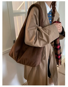 Detail of a large dark brown wool tote bag worn by a model in a minimalist setting
