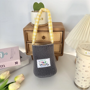 Detail of plush grey lambskin water bottle bag with yellow plaid strap and cute label