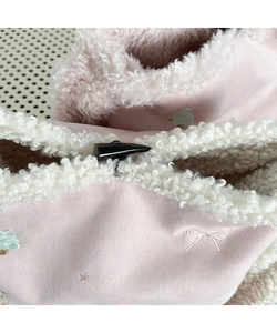Detail of pink plush crossbody bag featuring sheepskin trim and a horn toggle button