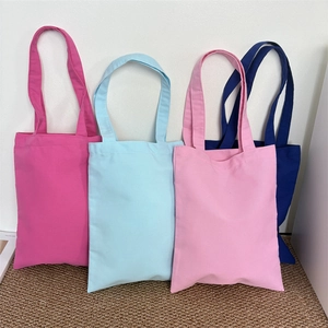 Detail of four colorful thickened canvas tote bags in pink, blue, rose, and navy blue