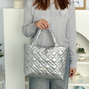 Close-up of a silver quilted tote bag with metallic finish and padded handles