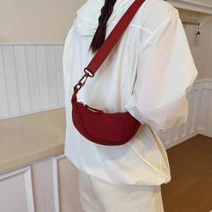 Burgundy water-resistant crossbody dumpling bag shown on model in a modern home setting