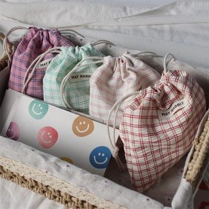 Close-up of assorted plaid drawstring pouches in a wicker basket with cotton texture