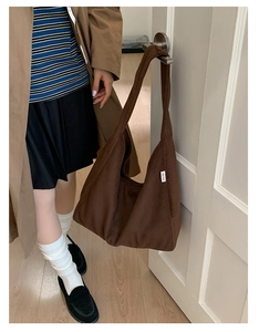 Detail of soft dark brown wool tote bag featuring a minimalist white textile label design