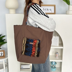 Detail of large brown tote bag featuring a plush lamb wool pocket with ethnic patterns