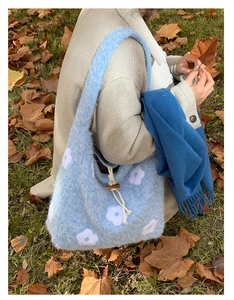 Detailed texture of blue plush shoulder bag with white flower embroidery and toggle