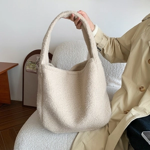 Detail of soft cream plush tote bag with wide strap on a stylish neutral trench coat