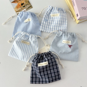 Detail of striped drawstring storage bags in assorted blue patterns with ribbon accents