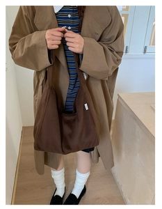 Close-up of deep brown wool tote bag with brand label on a brown trench coat outfit