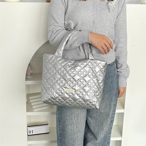Detailed view of silver quilted puff tote bag with metallic finish and brand label