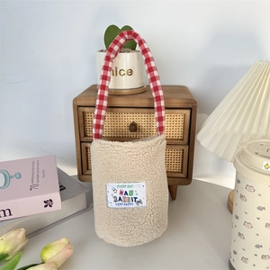 Detail of plush lamb wool bottle carrier with colorful rabbit patch and red checkered handle