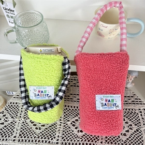 Detail of plush lamb wool bottle sleeve with checkered strap and MY RABBIT patch
