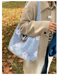 Detail of blue plush shoulder bag with floral embroidery and wooden toggle closure