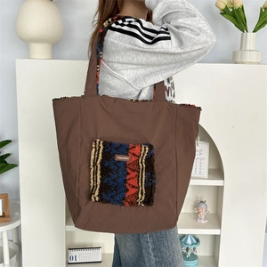 Brown tote bag with colorful faux fur patch pocket shown in a cozy lifestyle setting