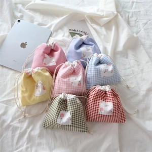 Détail de pochettes à cordon en coton à carreaux avec écussons floraux dans un décor doux