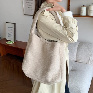 Chic beige faux shearling tote bag shown in use within a minimalist interior setting