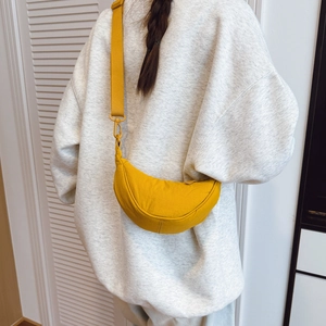 Detail of adjustable wide shoulder strap on yellow water-resistant crossbody dumpling bag