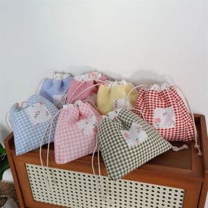 Détail de sacs de rangement à cordon en coton à carreaux de couleurs variées sur étagère