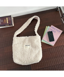 Macro view of cream plush sherpa shoulder bag featuring SEEYOU logo and soft texture