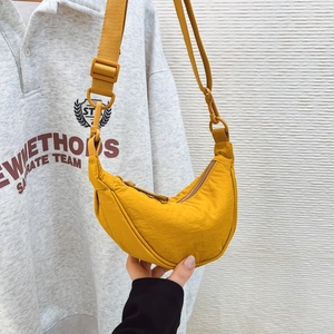 Detail of adjustable strap and matte buckle on a bright yellow nylon crescent crossbody bag