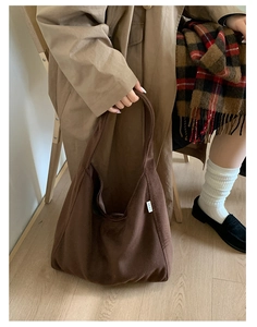 Detail shot of the plush dark brown wool tote bag featuring a brand label and wide shoulder strap