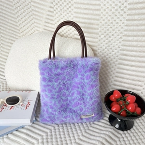Detail of purple faux fur leopard print handbag with round handles and woven brand label