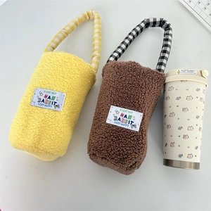 Detail of soft plush lamb wool bottle sleeve with checkered strap and woven label