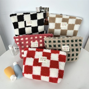 Close-up of five colorful checkered plush cosmetic bags with soft fleece texture