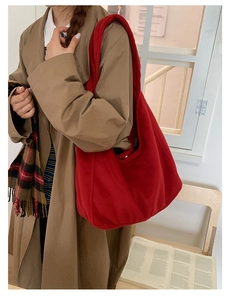 Detail of red wool tote bag with soft texture shown on model in warm indoor light