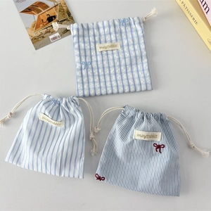 Detail of striped drawstring storage bags with cute bow embroidery and soft fabric texture